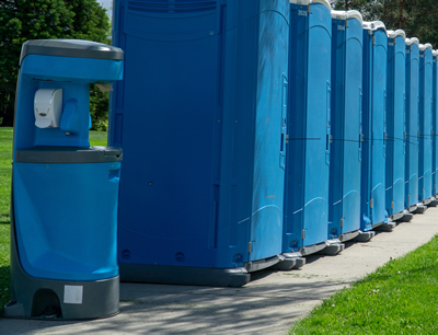 portable hand washing station next to a line of portable toilets