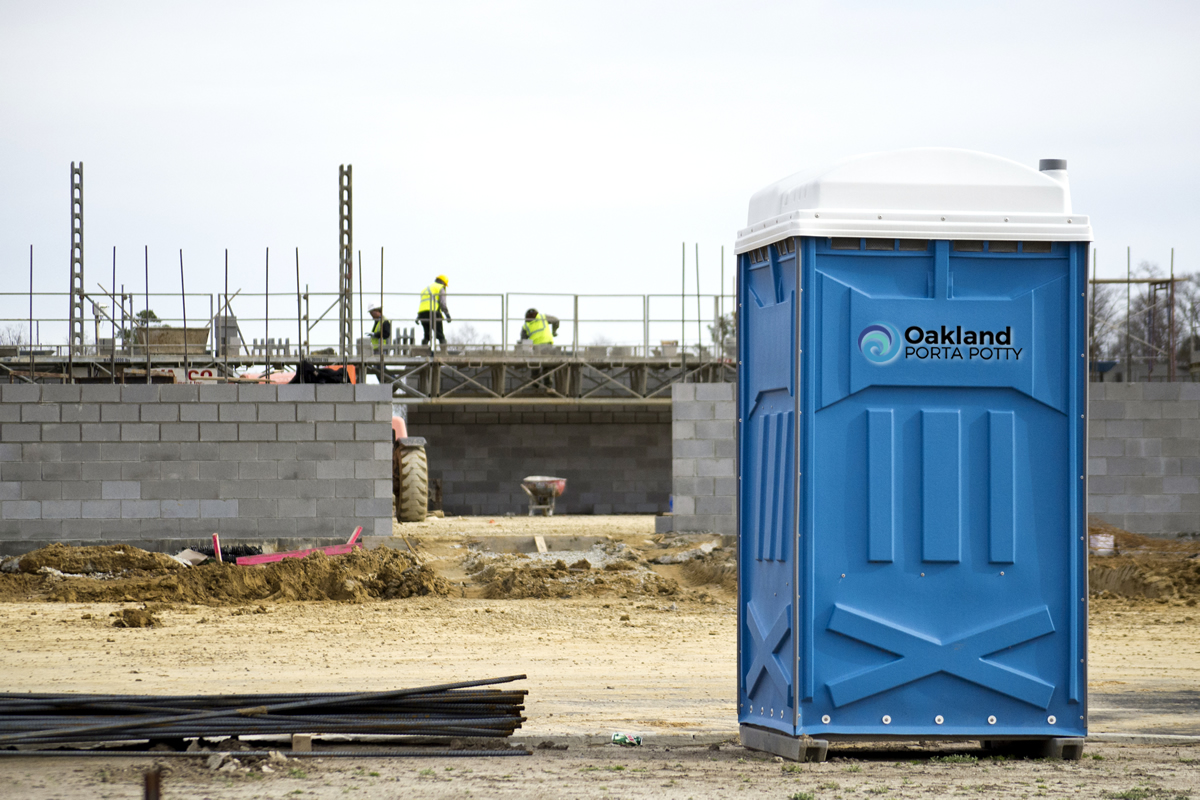 Portable toilet on a job site with a crew working in the background